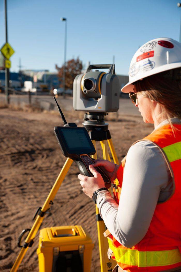 Construction worker operating the Trimble TSC7 Data Collector and Controller on a construction site.