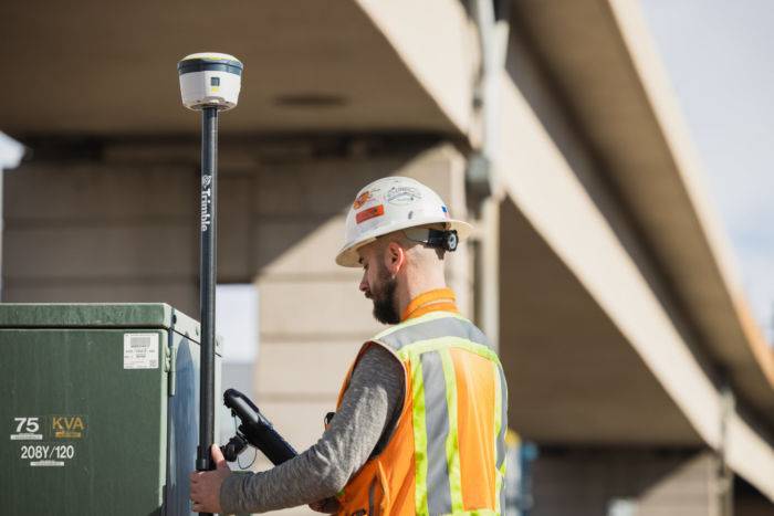 Construction worker operating Trimble R580 GNSS System in the field.